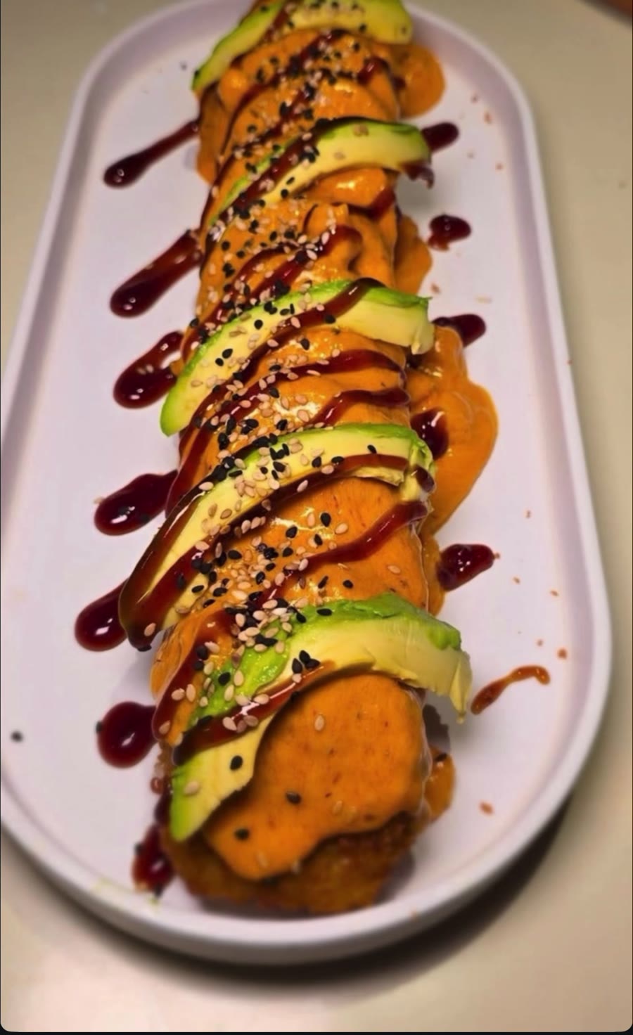 Roll con aguacate, salsa de anguila y ajonjolí en charola blanca