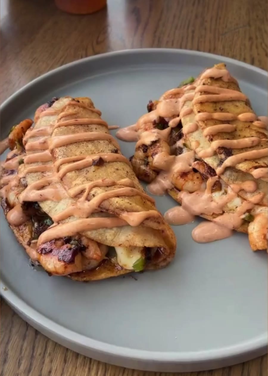 Dos tacos dorados con salsa cremosa encima